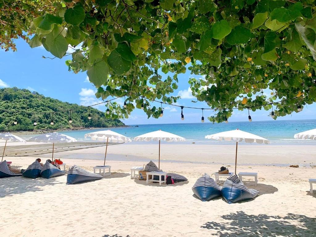 una spiaggia con ombrelloni e persone sedute sulla sabbia di Kerala Coco Resort a Ko Samed