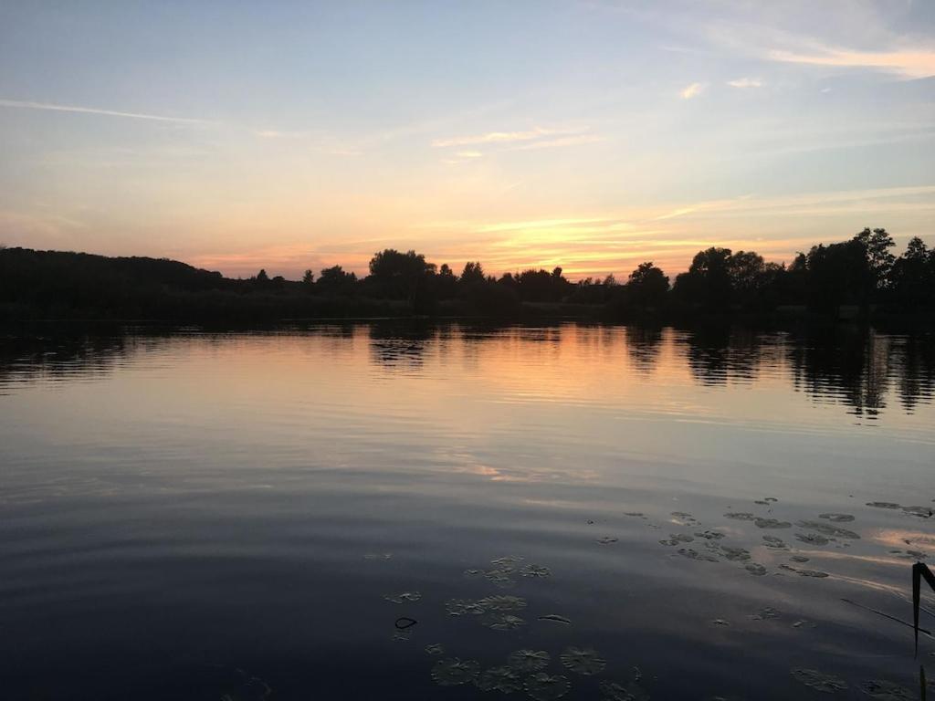 a large body of water with a sunset in the background at FEWO am See Zarrendorf in Zarrendorf