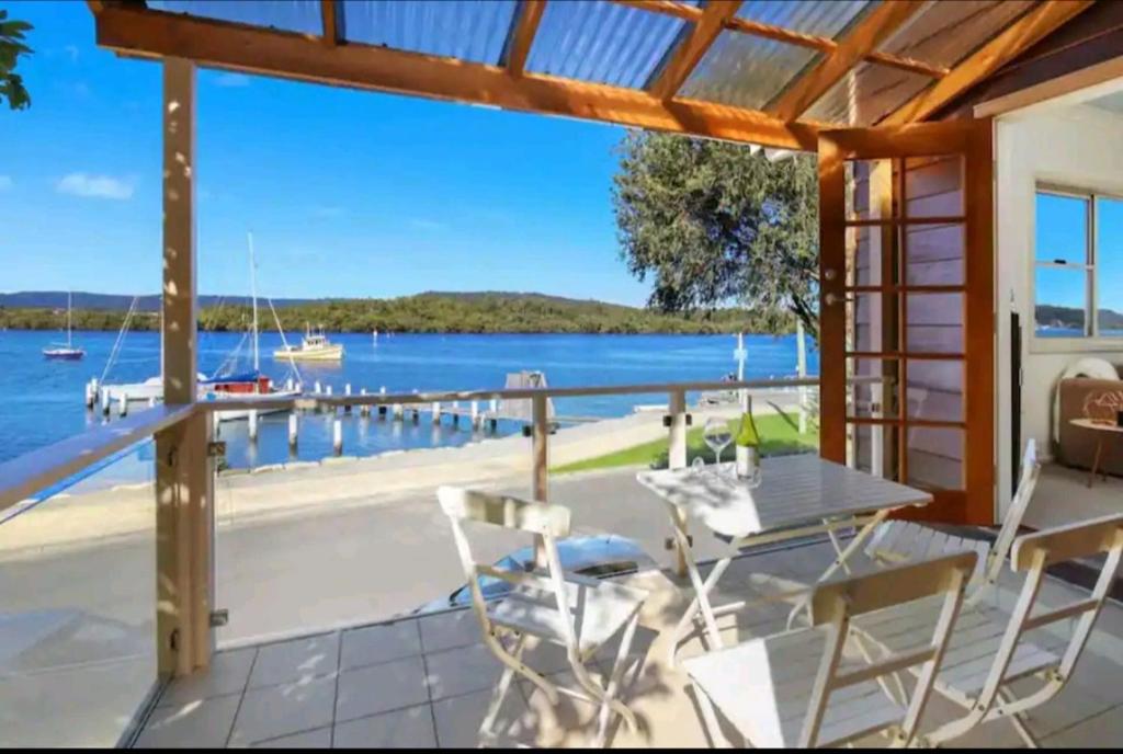 a patio with a table and chairs and a view of the water at Central Coast Jetty House in Saratoga