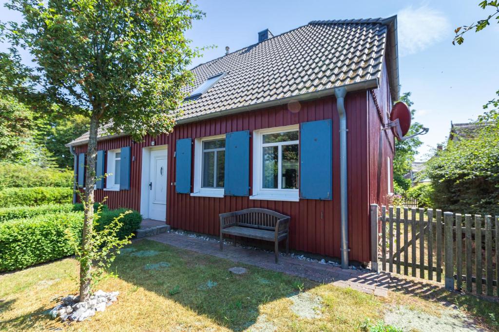 een rood tiny house met een bank in de tuin bij Kapitänshaus - Kajüte in Ahrenshoop