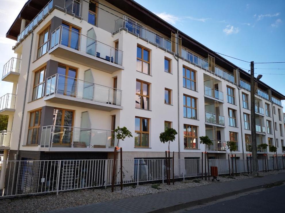 a white building with a fence in front of it at Apartament Baltic Marina in Dziwnówek