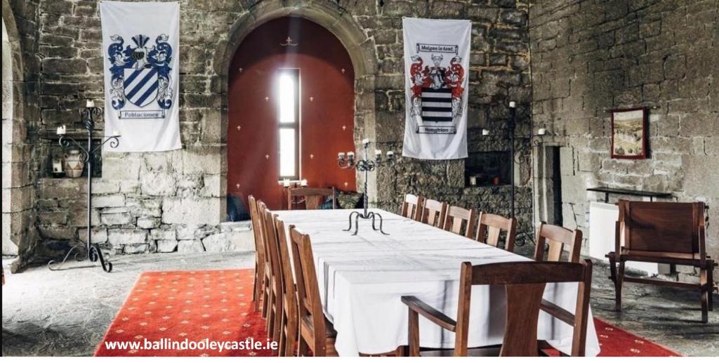 een kamer met een lange tafel met stoelen en vlaggen bij Ballindooley Castle in Galway