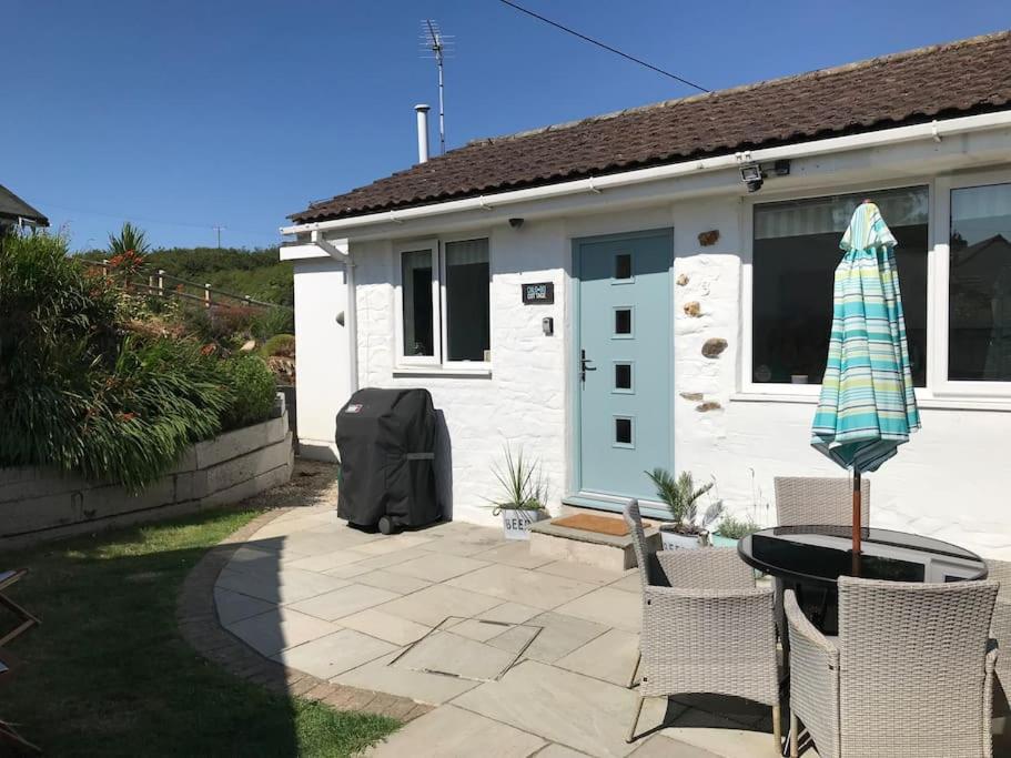 a house with a patio with a table and an umbrella at ChloBo Cottage near Watergate Bay, by the sea in Porth