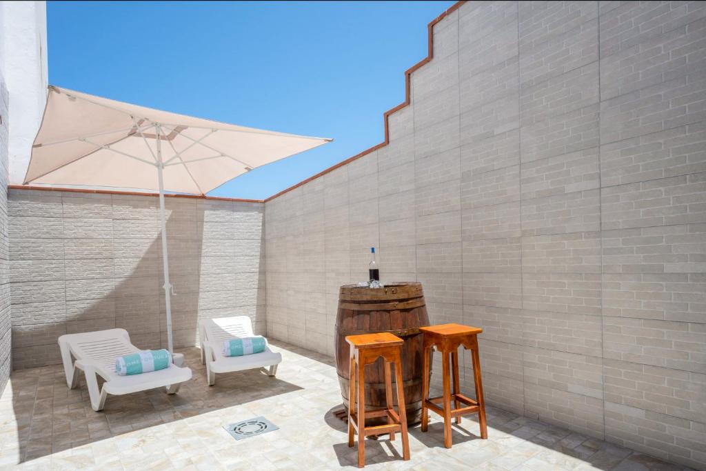 Bonito apartamento a 100 m de la playa في Arico: فناء مع كرسيين ومظلة