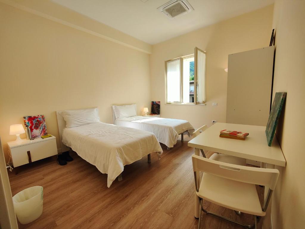 een kamer met 2 bedden, een bureau en een spiegel bij Casa dello Studente in Vittorio Veneto