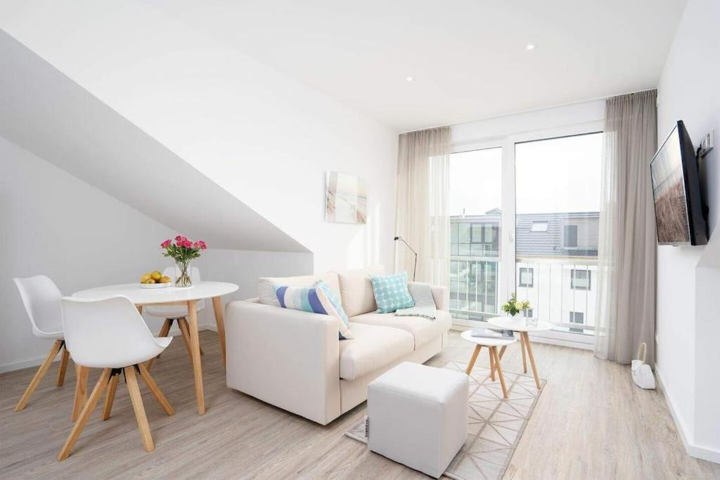 sala de estar con sofá blanco y mesa en SEASIDE - Neubau mit Meeresblick en Sierksdorf