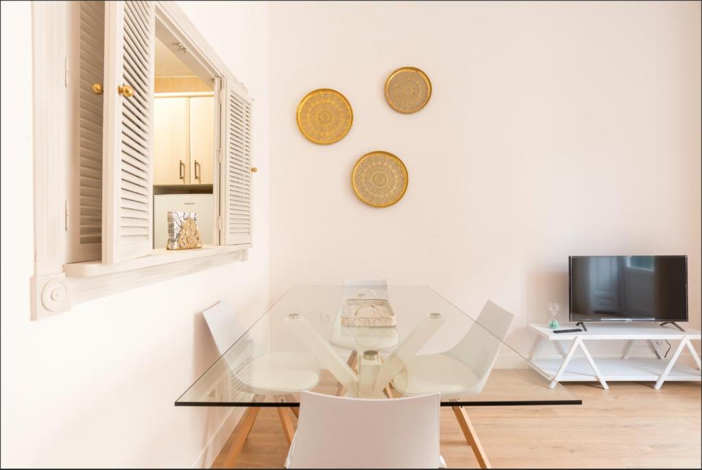 uma sala de jantar com uma mesa de vidro e uma televisão em Merced10 2C em Málaga