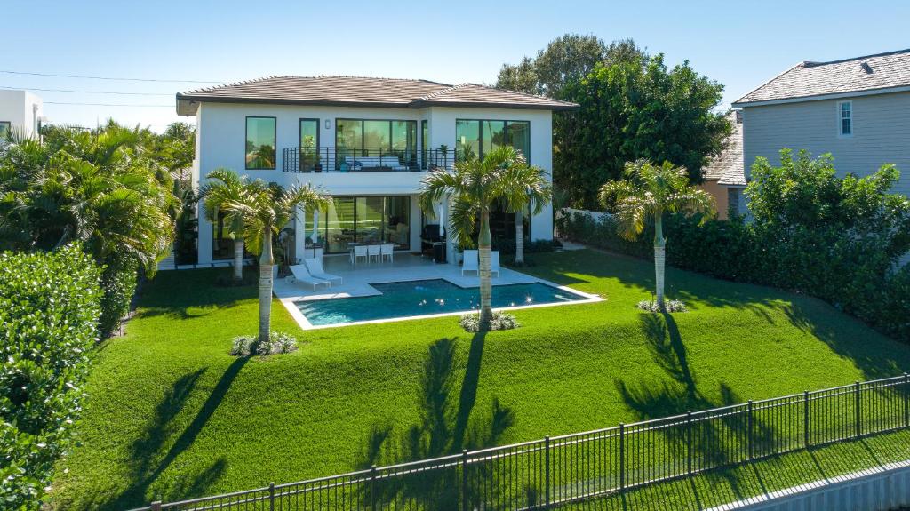 a house with a yard with a pool and palm trees at The Delray Hideaway in Delray Beach
