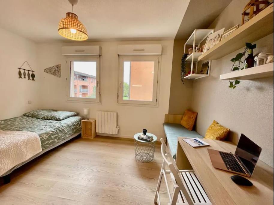 - une chambre avec un lit et un bureau avec un ordinateur portable dans l'établissement Studio Orchidée - Métro Arènes - Hopital à 5 mn, à Toulouse