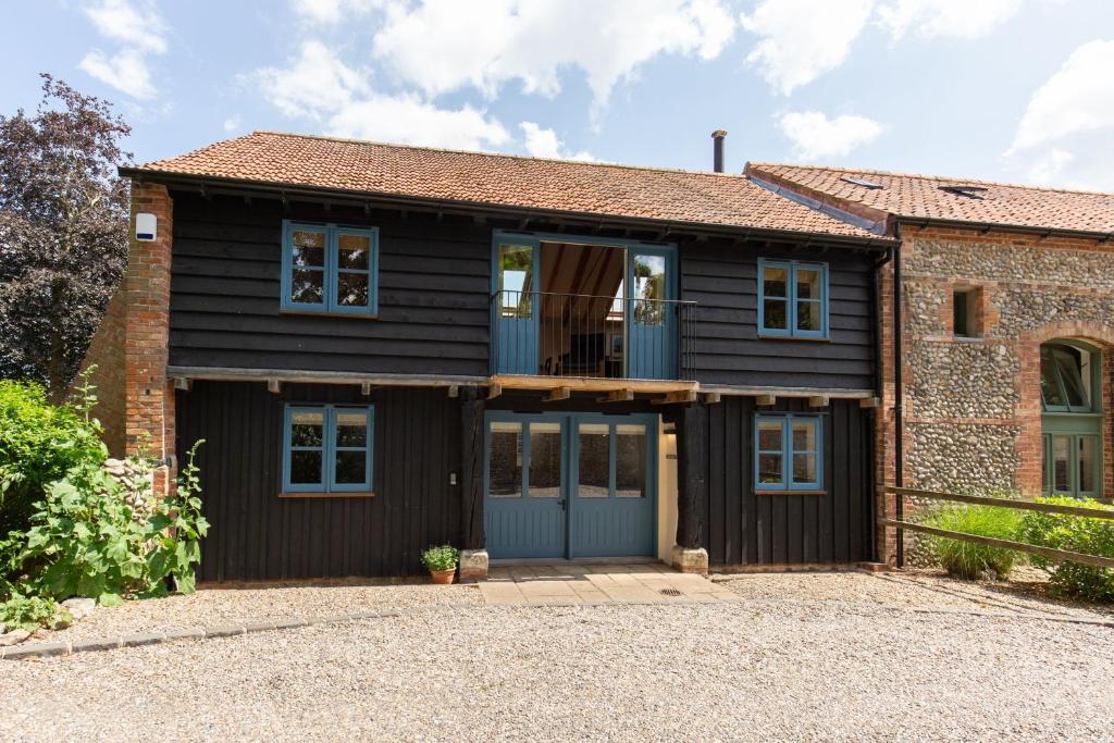 a brick house with a blue garage at Owl Barn in Morston