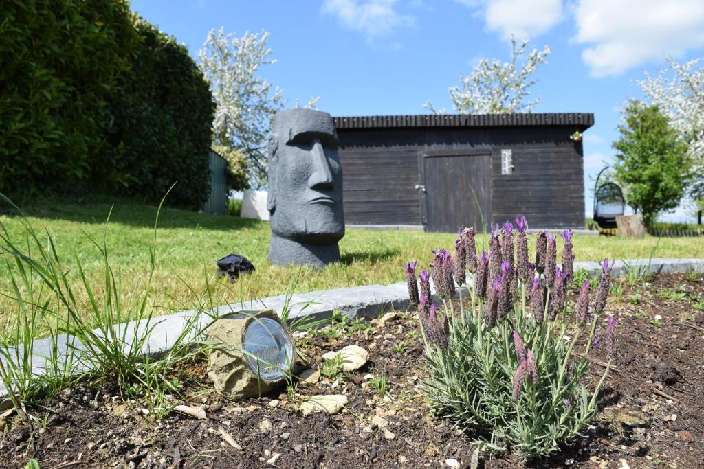 a statue of a face in a garden with purple flowers at Naturgeflüster Chalet in Morbach