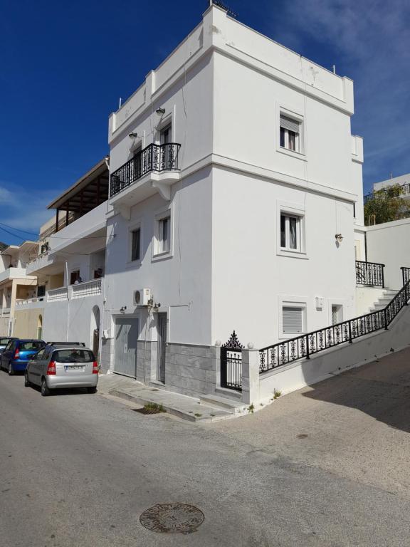 Un bâtiment blanc avec une voiture garée devant. dans l'établissement Art House Syros, à Ermoúpoli