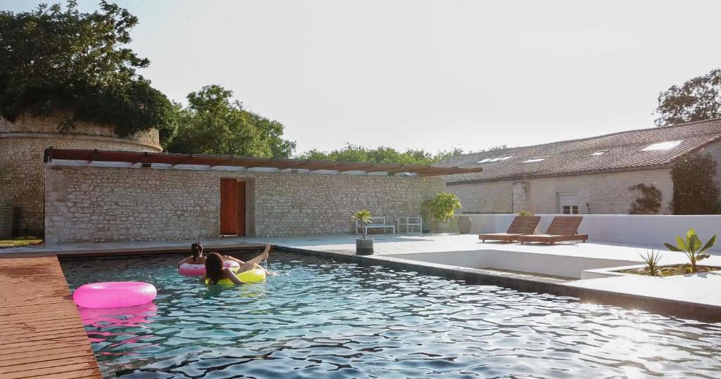 uma piscina com duas pessoas a flutuar numa bola insuflável em Gite de St Hilaire em Soubise