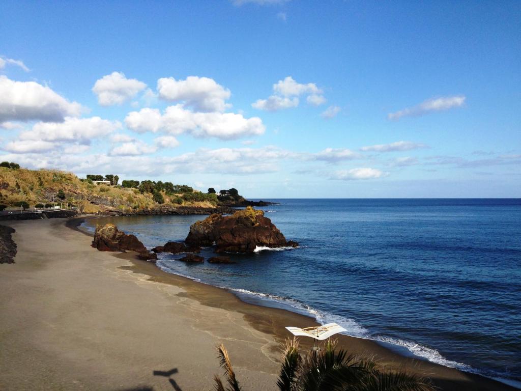 a view of a beach with rocks and the ocean at Vinha da Areia Beach Hotel in Vila Franca do Campo