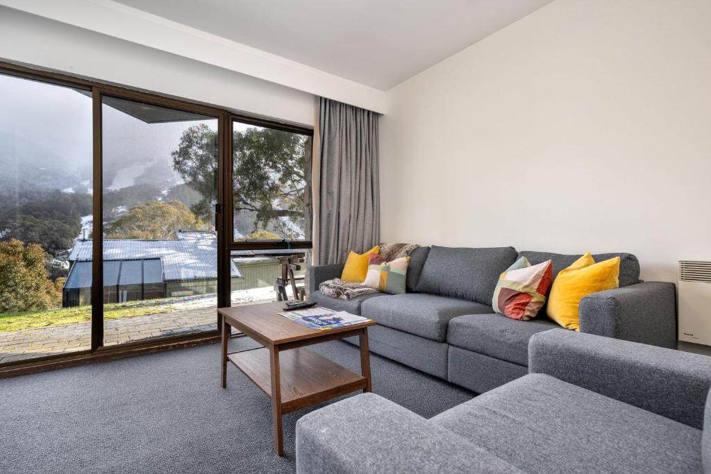 a living room with a couch and a table at Lantern 1 Bedroom Patio Apartment with alpine view in Thredbo