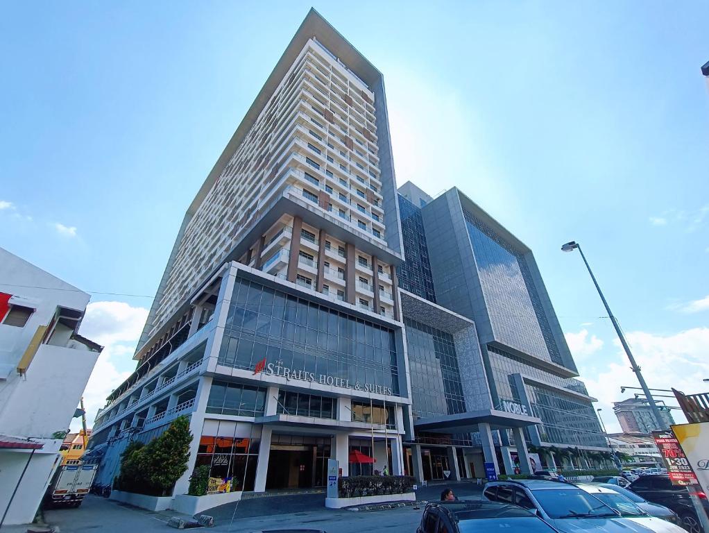 マラッカにあるStraits Residence Melaka Private Suitesの車が目の前に停まった高い建物