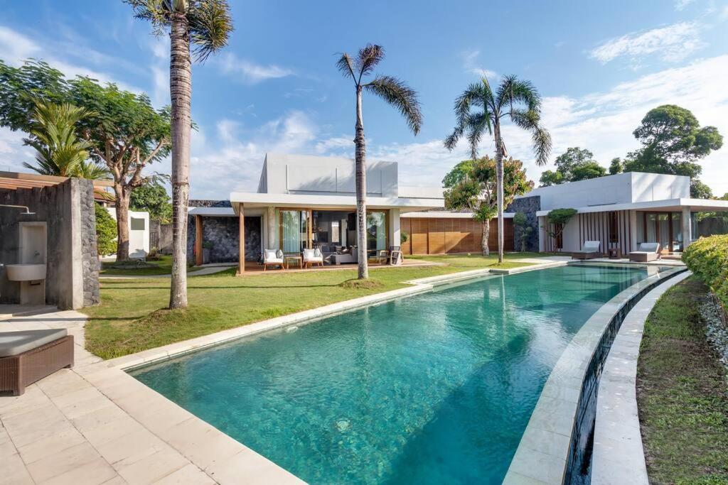 una piscina frente a una casa con palmeras en Villa Mila, en Dalung