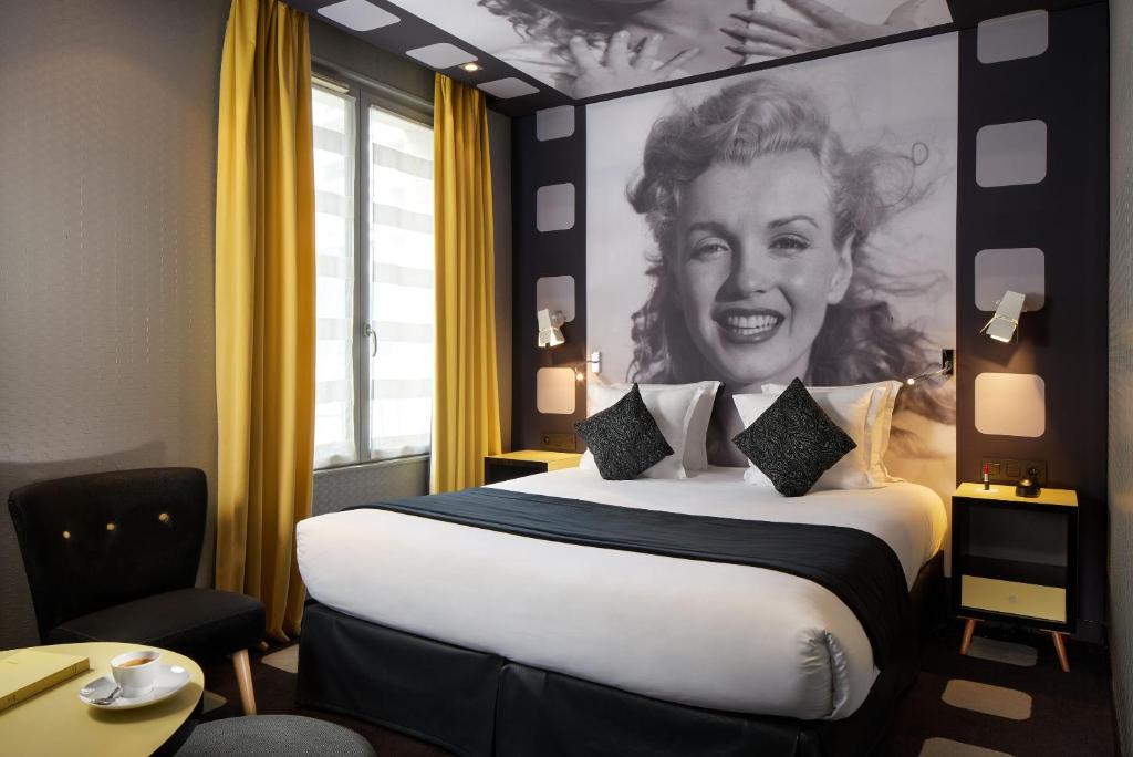 una camera d'albergo con un grande letto e un dipinto di una donna di Platine Hotel a Parigi