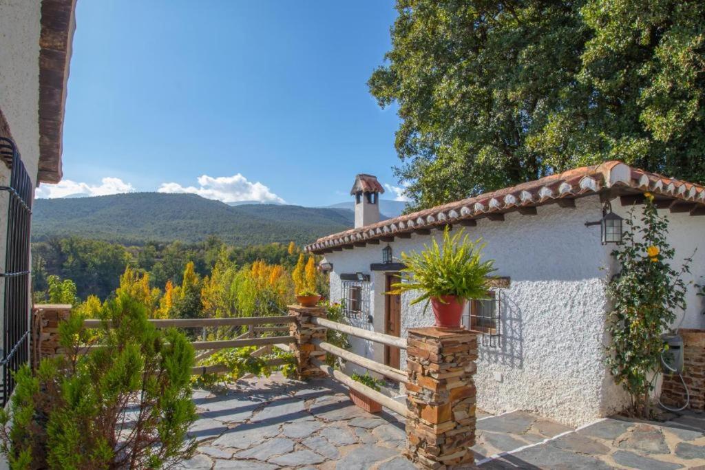 a white house with a fence and mountains in the background at Molino de Santa Águeda in Jerez del Marquesado