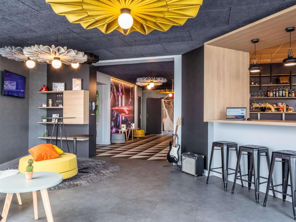 um quarto com um bar com um sofá amarelo e banco em ibis Compiegne em Compiègne