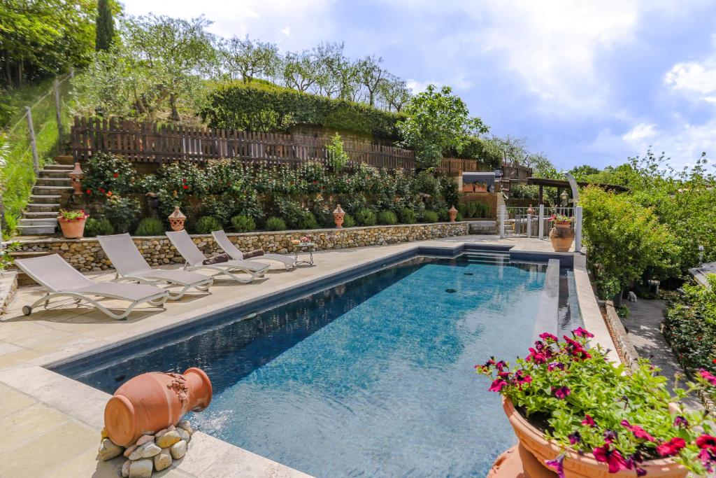 a swimming pool in a yard with chairs and flowers at Villa Lolù in Terranuova Bracciolini