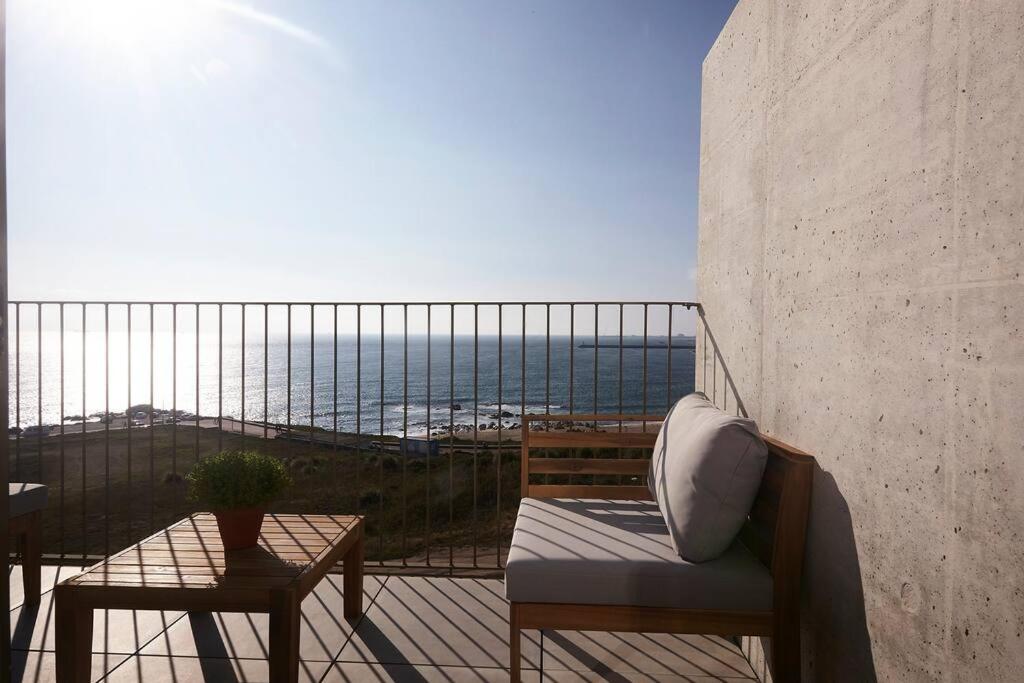 a balcony with a chair and a table and the ocean at Porto Sunset suite in Vila Nova de Gaia