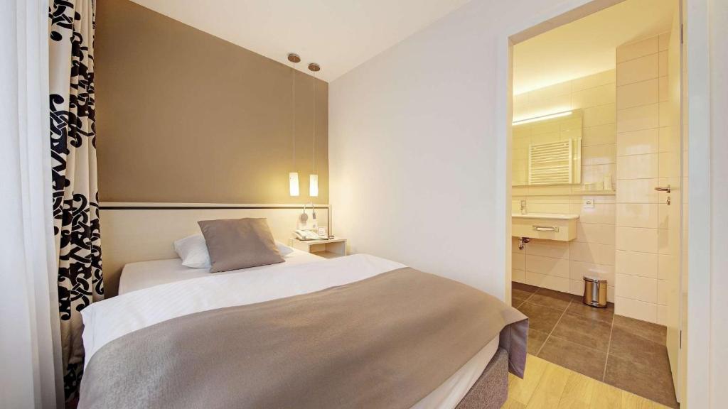 a small bedroom with a bed and a bathroom at Hotel Schwanen Stuttgart Airport/Messe in Filderstadt