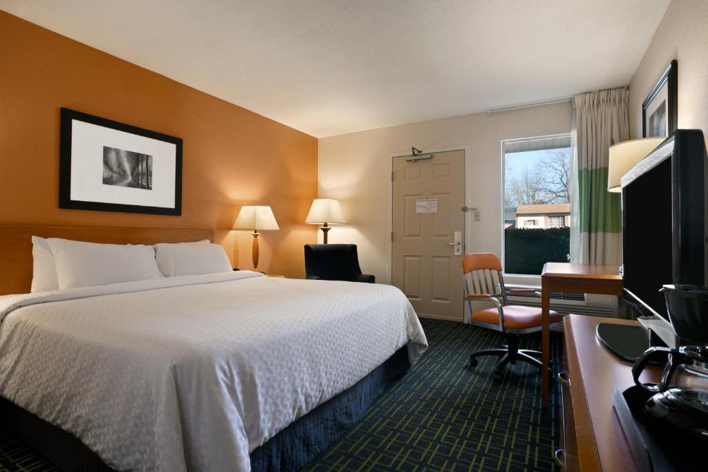 a hotel room with a bed and a desk and a television at Days Inn by Wyndham Chattanooga/Hamilton Place in Chattanooga