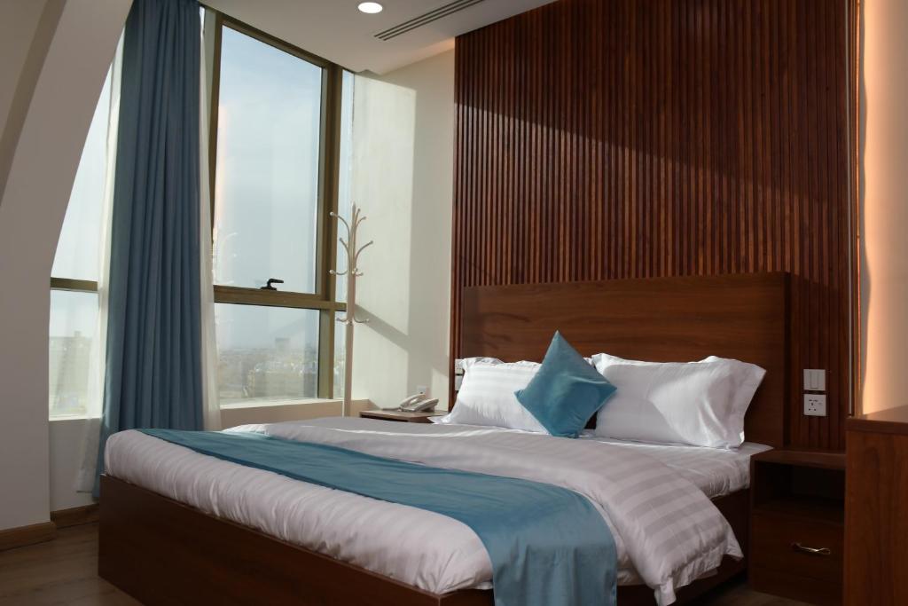 1 dormitorio con 1 cama grande y ventana grande en فندق ايلاف الشرقية 2 Elaf Eastern Hotel 2 en Sayhāt