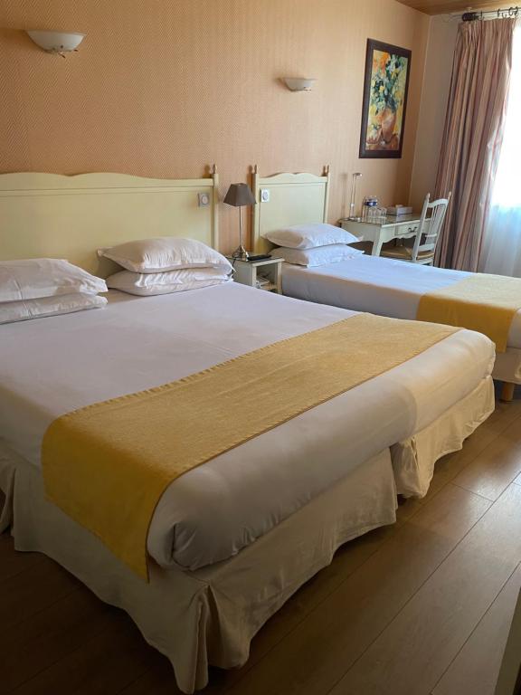 two beds in a hotel room with a table at Hôtel Le Médiéval Palais des Papes in Avignon