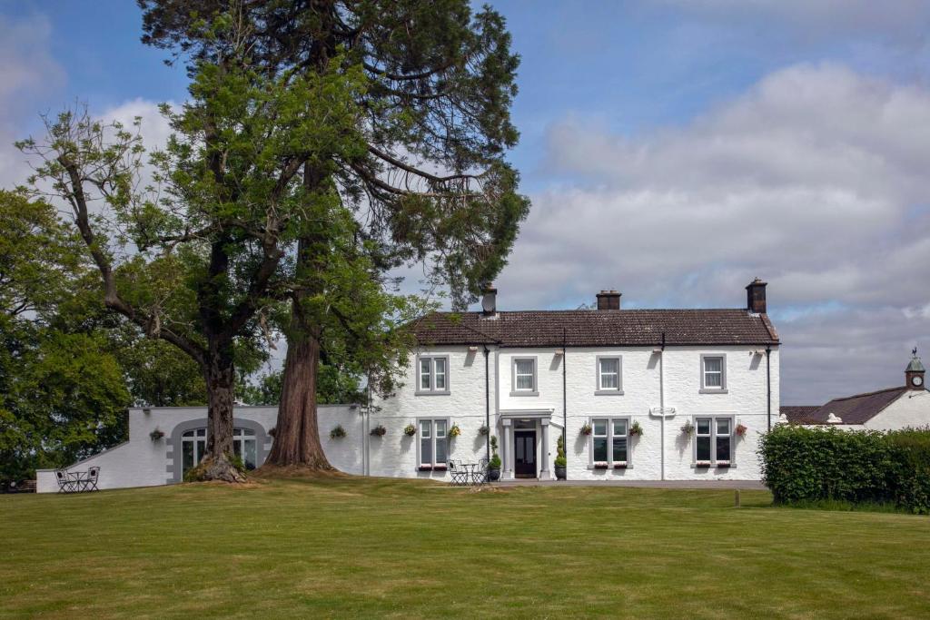 una grande casa bianca con un grande albero di Dryfesdale Hotel - BW Signature Collection a Lockerbie