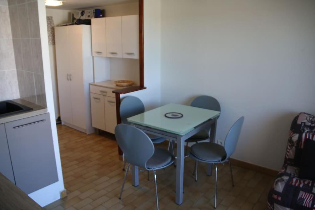een kleine keuken met een tafel en stoelen en een koelkast bij Studio 141 Port Soleil B1 au village naturiste in Cap d'Agde