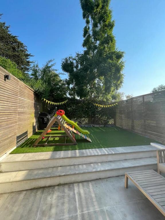 a playground with a slide in a backyard at Beautiful Family-Friendly 4BD House - North Sheen in Kew Gardens
