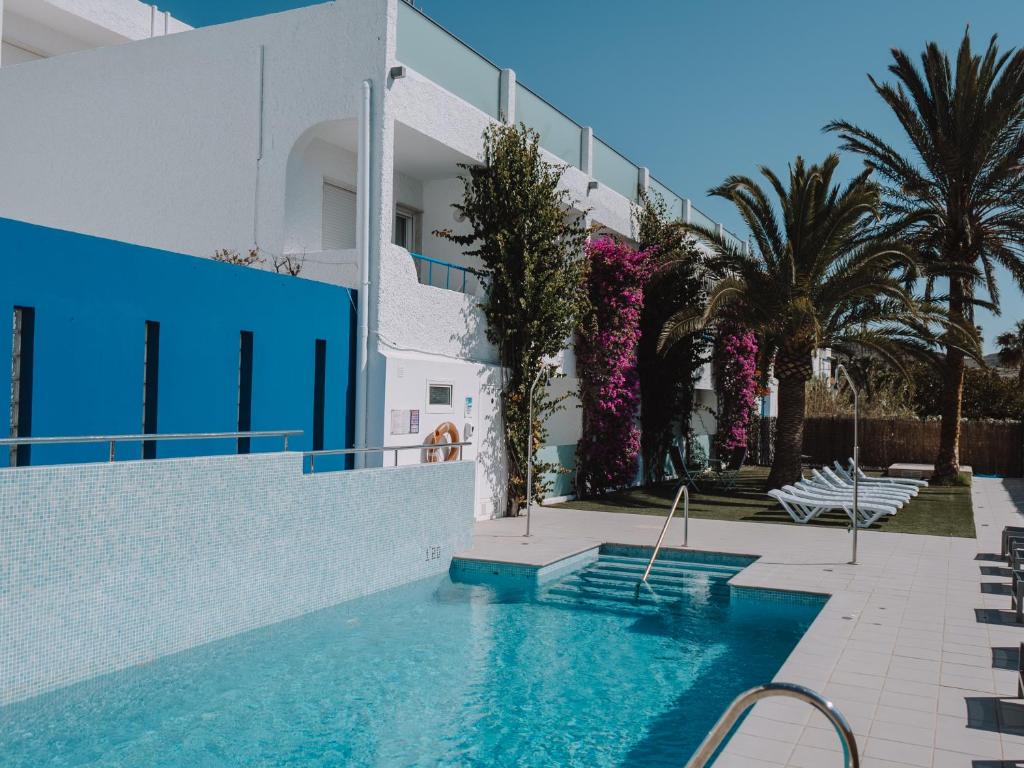 a swimming pool in front of a building with palm trees at Hostal Las Gaviotas del Cabo in San José