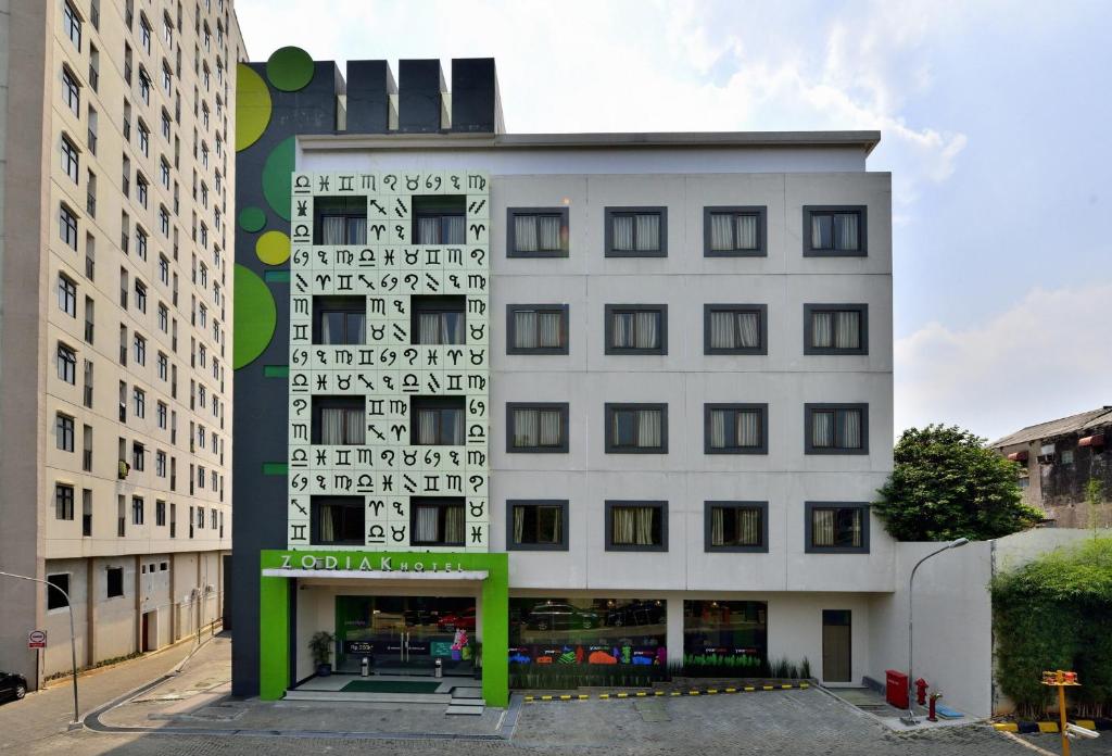 Zodiak MT Haryono by KAGUM Hotels في جاكرتا: مبنى ذو واجهة خضراء وبيضاء