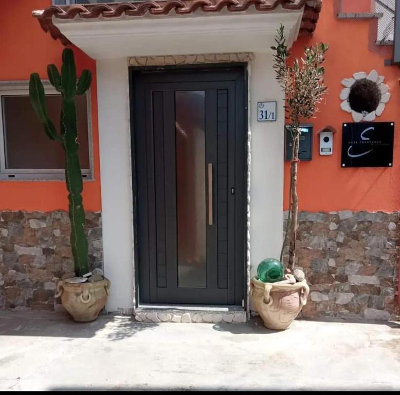 una puerta negra de una casa con dos macetas en Casa Francesca en Mercato San Severino