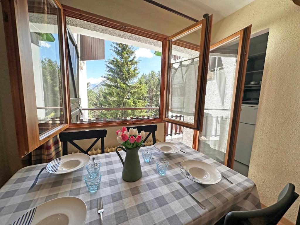 Una mesa con dos platos y un jarrón de flores. en Apartamentos Confort Formigal 3000, en Formigal