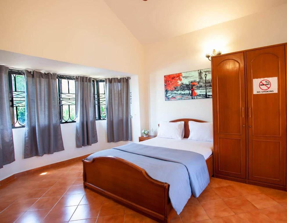 Schlafzimmer mit einem Bett, einem Schrank und Fenstern in der Unterkunft 'Golden Coral' 2bhk Benaulim Beach villa Goa in Margao