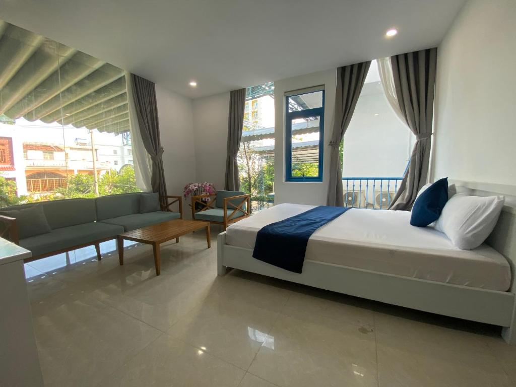 a bedroom with a bed and a couch and windows at Alicia Hotel in Tuy Hoa