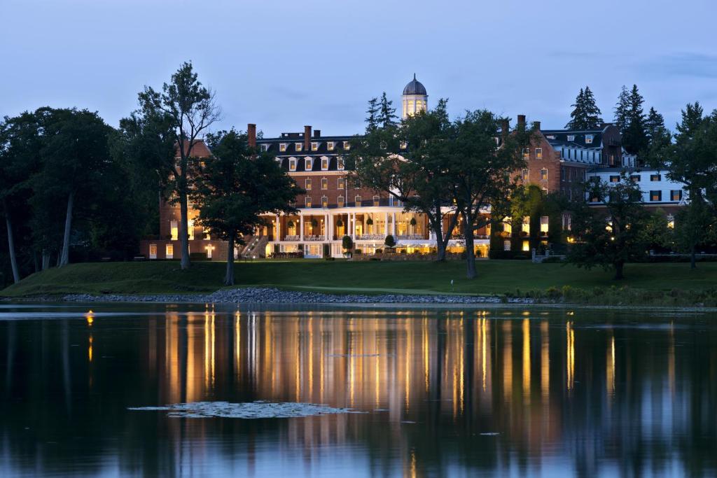 ein großes Haus mit einem Teich davor in der Unterkunft The Otesaga Resort Hotel in Cooperstown