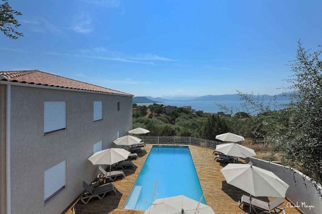 a swimming pool with umbrellas and chairs and a building at Casa Soprana in Porto Pollo