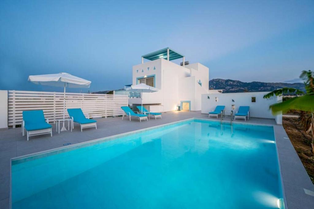 a swimming pool with blue chairs and a house at Xenos Villa 7 with a Private pool near the sea in Tigaki