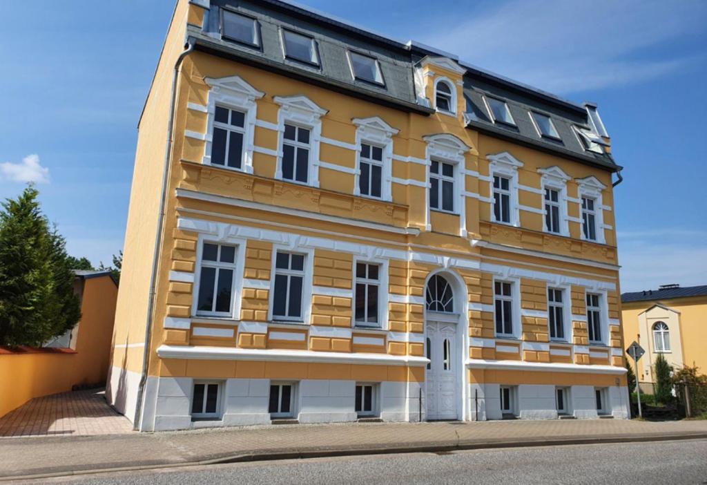 un edificio amarillo y blanco al lado de una calle en Alt-Berliner Schwanenhof - Ferienwohnungen Lychen en Lychen