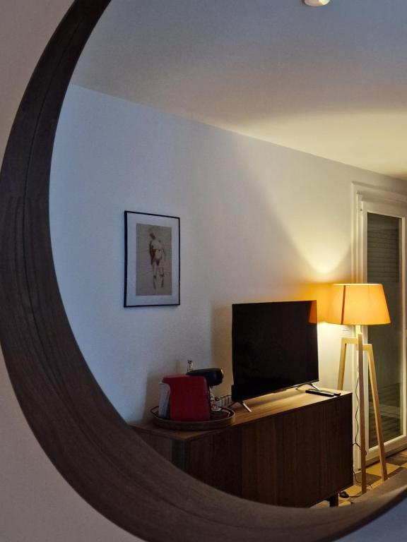 a mirror reflecting a room with a desk with a television at maison PING ,en face des arènes in Béziers