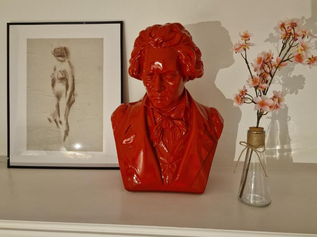 a red statue sitting on a shelf next to a vase with flowers at maison PING ,en face des arènes in Béziers