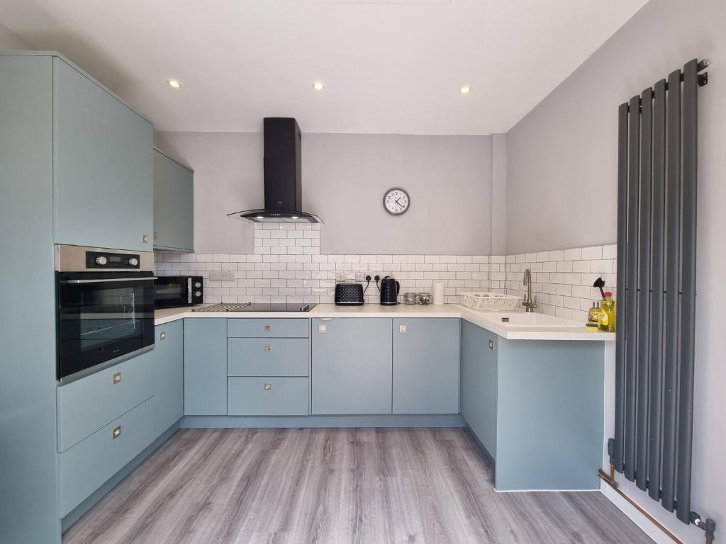 uma cozinha com armários azuis e electrodomésticos brancos em The Forge by Cliftonvalley Apartments em Bristol