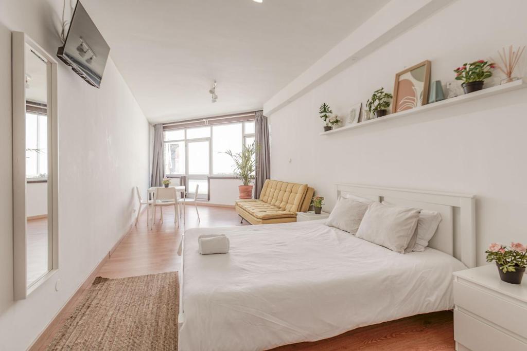 una camera bianca con un letto e una sedia di Travel & Live Aliados Apartment a Porto