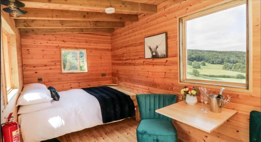 Shepherds Hut by Stepney Stays في سكرابورو: غرفة نوم بسرير وطاولة وكراسي