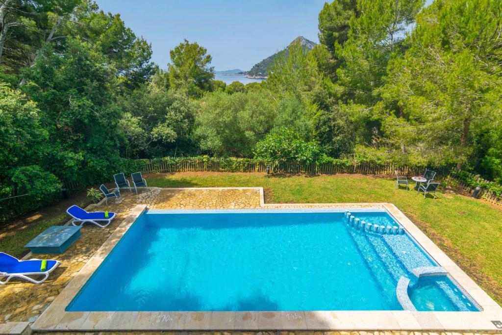 a swimming pool in a yard with chairs and trees at Can Mir Sa Posada des Pagès in Formentor