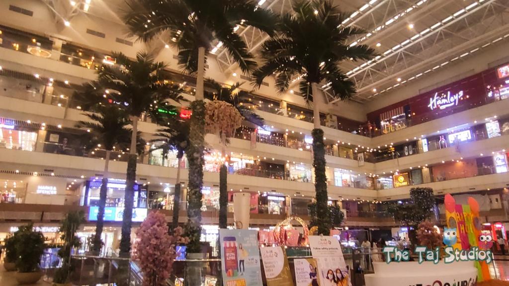 un gran edificio con palmeras en un centro comercial en Top Luxuries Couple Friendly Stay in Gaur Mall by Taj Studios, en Ghaziabad